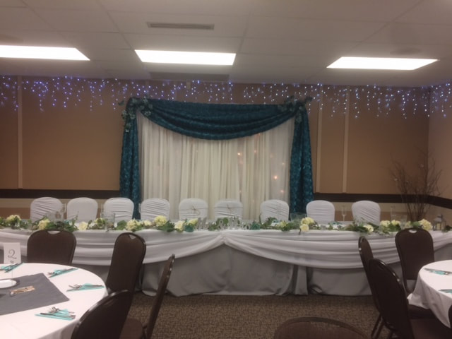 Head table with draped backdrop and floral garland
